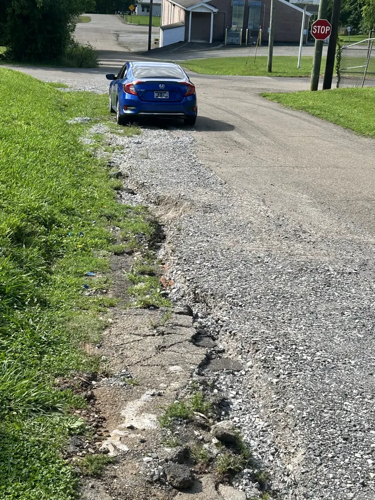 Eroded gravel shoulder along a driveway before repair in Knoxville, Tennessee