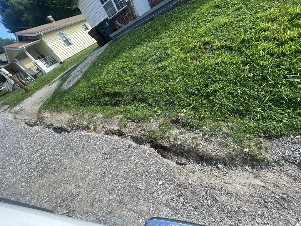 Washed-out shoulder beside a residential drive before repair in Knoxville, TN