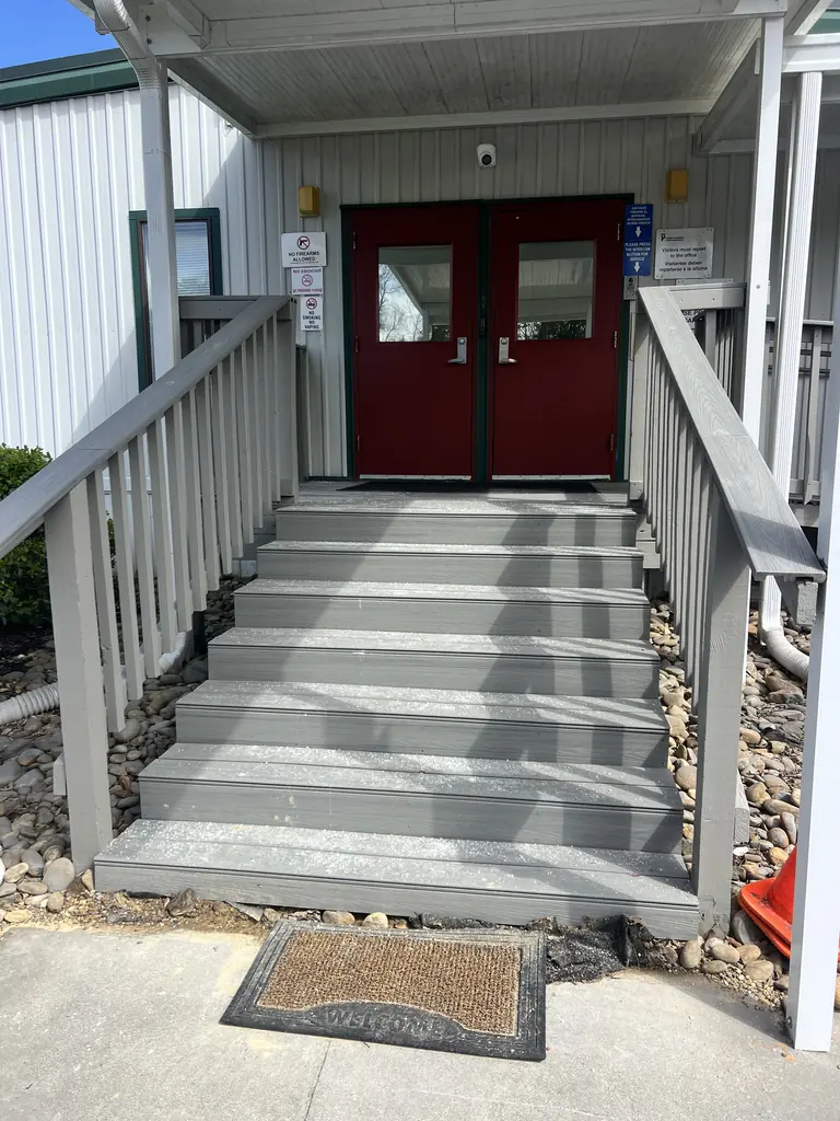 Stairs with railings on both sides leading to a red double-door entrance