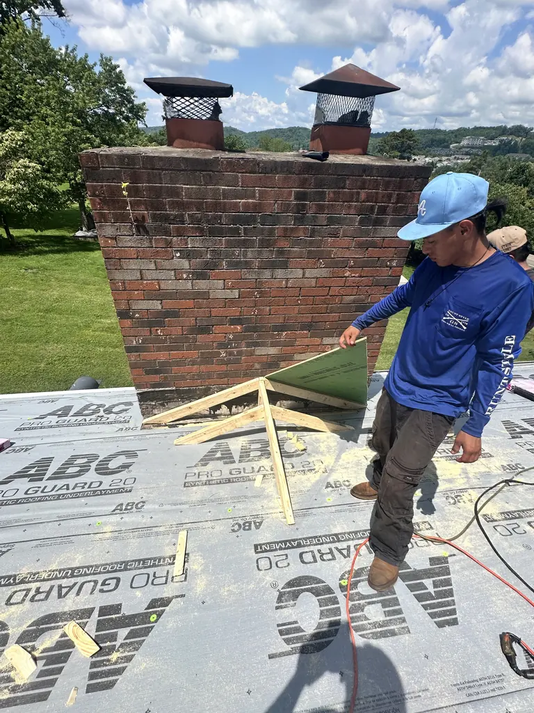 Crew member working the underlayment around a brick chimney in Knoxville, Tennessee